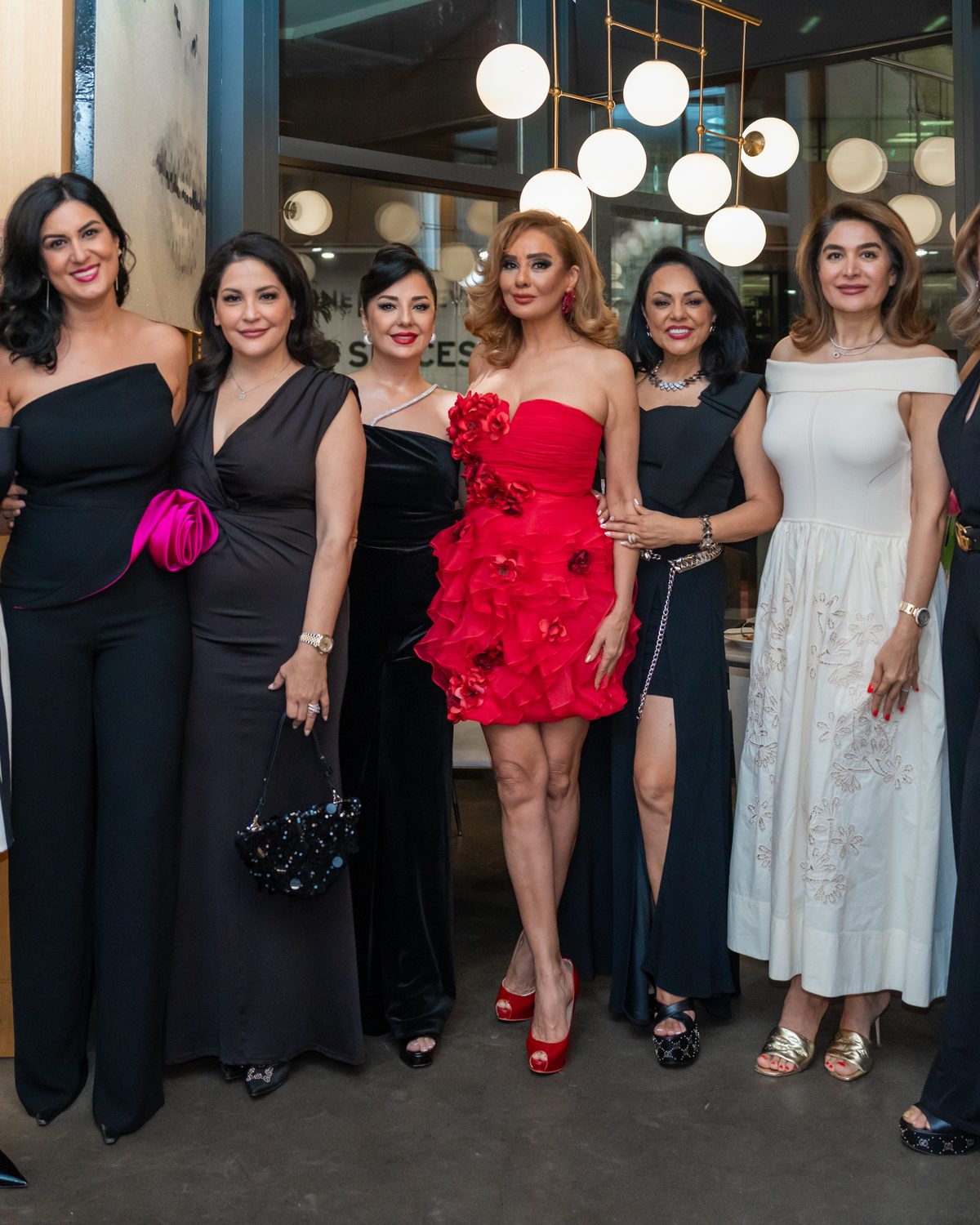 Group of guests in evening wear posing together at an indoor event