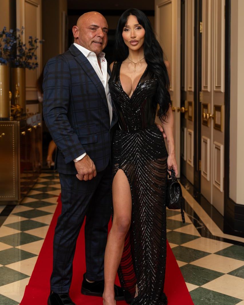 Couple posing on a red carpet at a Toronto gala, man in a dark suit and woman in a sequined gown