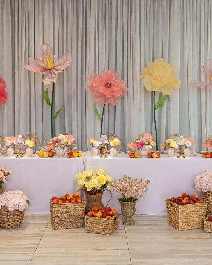 Rows of flower arrangements in baskets on a long table at a styled event